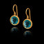 Gold earrings with synthetic emerald gemstones on a black background