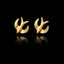Front view of gold stud earrings shaped like swallows in flight on black background.