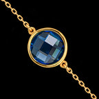 Close-up detail of the round faceted synthetic blue topaz gemstone set in a gold-plated bezel on the bracelet chain.
