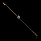 Full view of the gold plated 925 sterling silver chain bracelet featuring a round blue topaz gemstone and an adjustable extender chain.