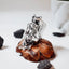  Large sculptural silver ring with a dramatic crumpled free-form polished surface displayed on a pine cone with black stones around it, side view.