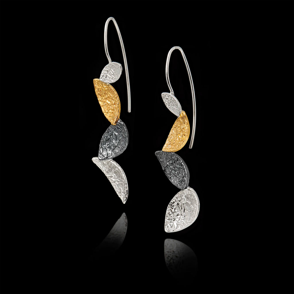 Pair of earrings with gold and silver leaf-like designs on a black background