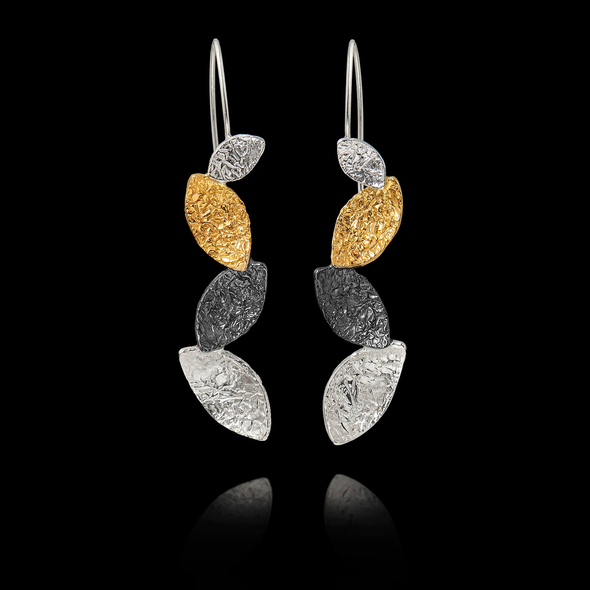 Pair of earrings with hammered gold and silver leaf-like designs on a black background Main image