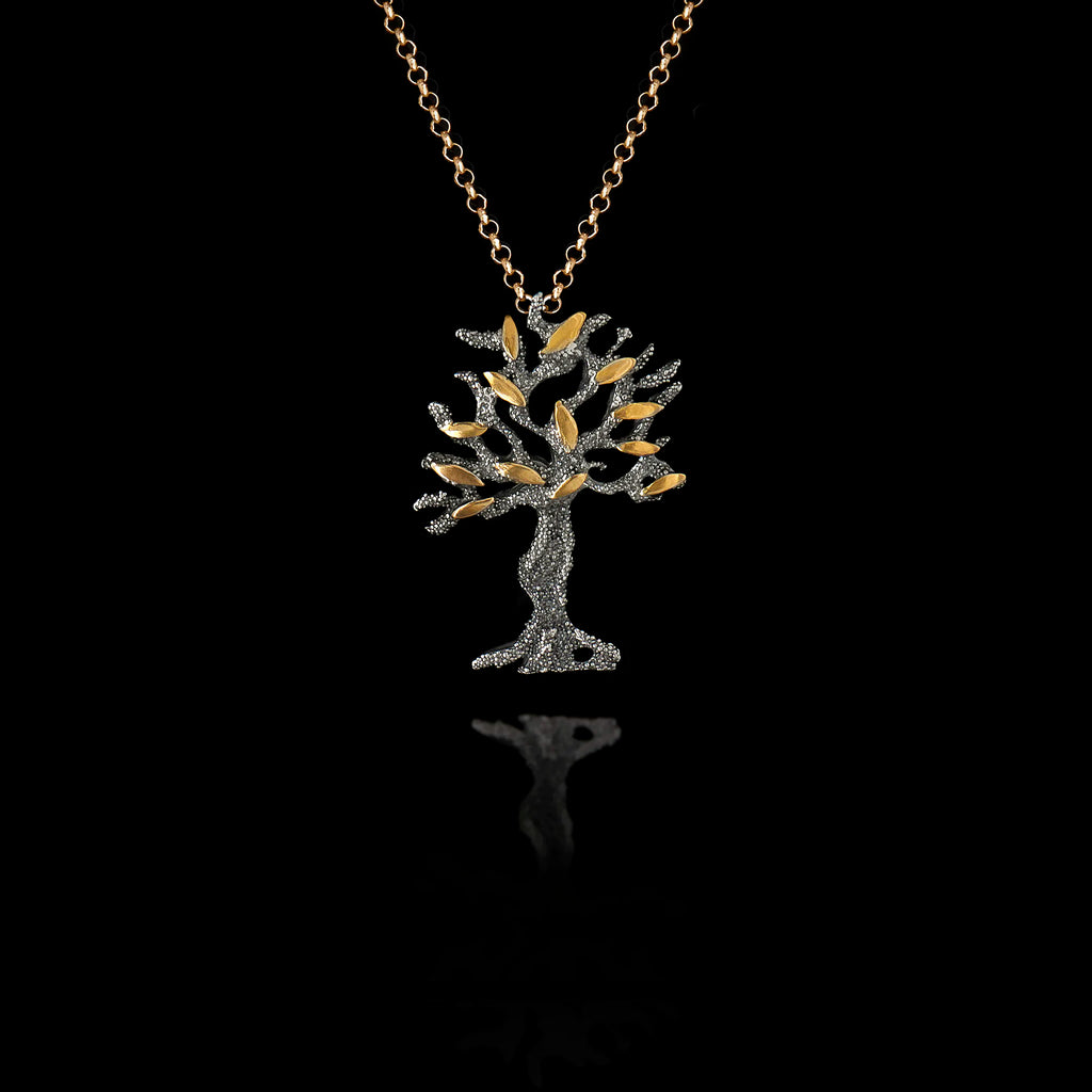 Oxidised silver olive tree pendant with gold leaves on a chain against a black background