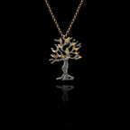 Oxidised silver olive tree pendant with gold leaves on a chain against a black background