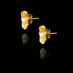 Angled side view of organic-shaped gold stud earrings with a wavy shell-like texture and a central white pearl.