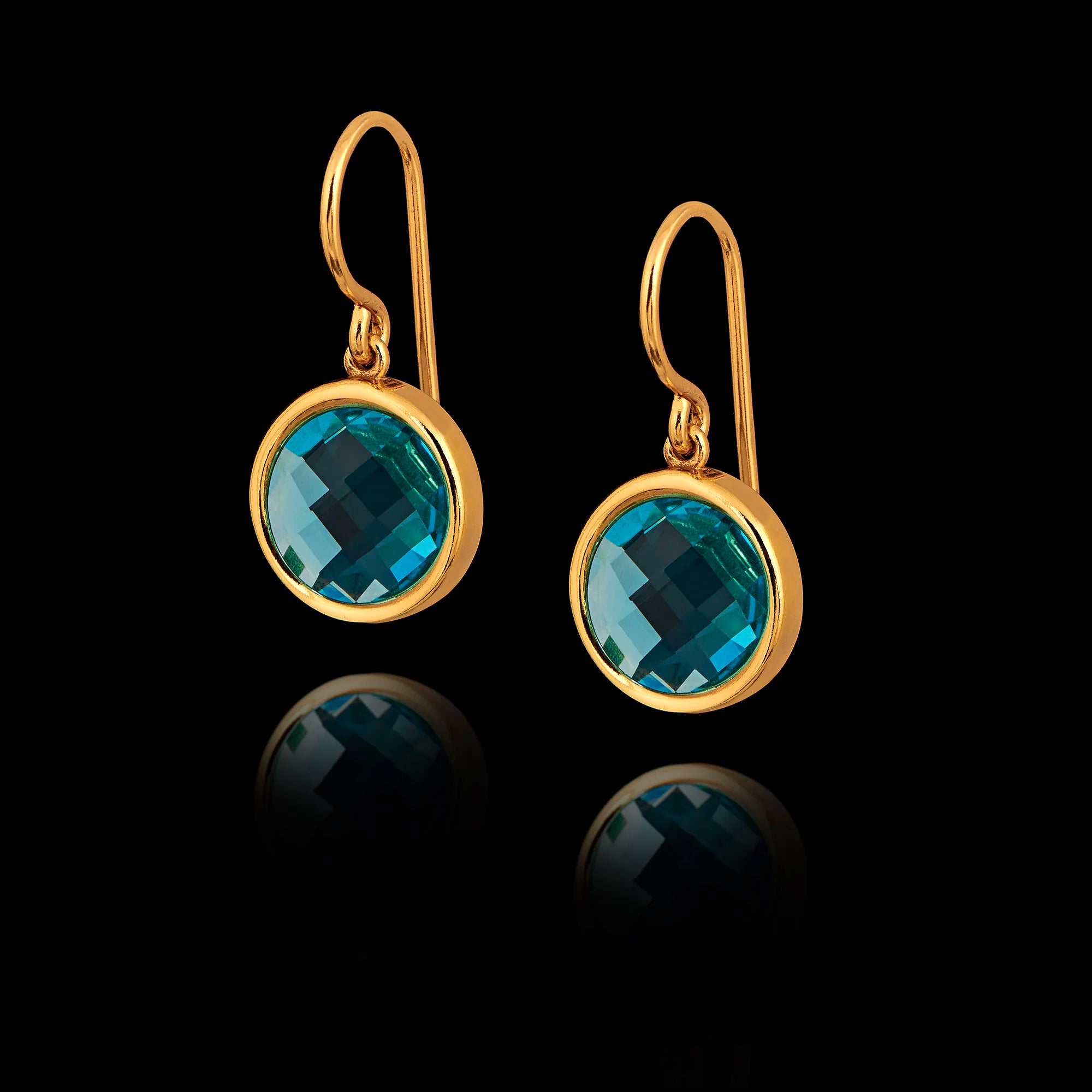 Gold earrings with synthetic emerald gemstones on a black background