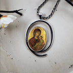 Silver pendant with religious icon on a textured surface