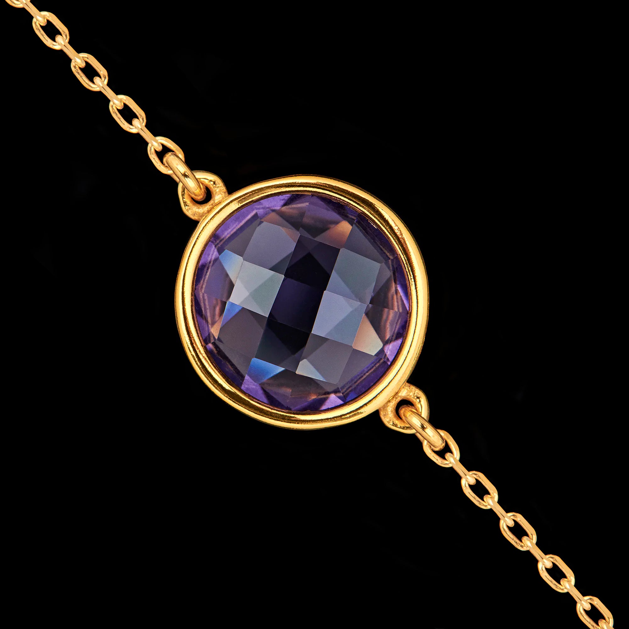 Close-up detail of the round faceted synthetic amethyst gemstone set in a gold-plated bezel.