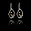 Pair of silver earrings with gold fish design on a black background