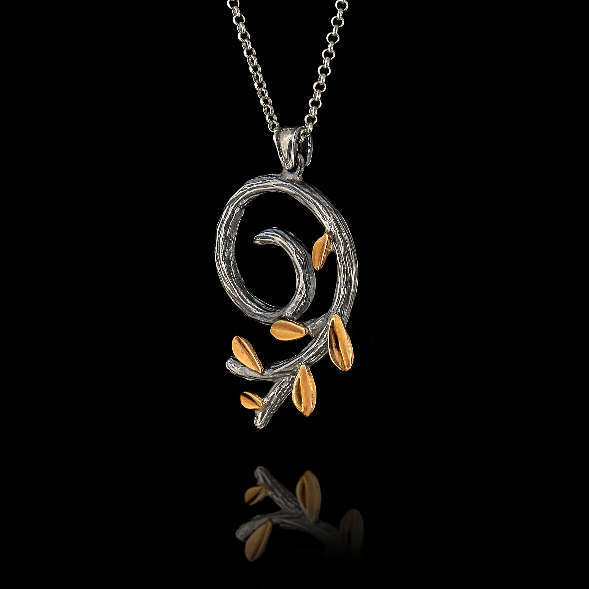 Perspective view of a silver spiral olive branch pendant on a chain, featuring an oxidized stem and gold-plated leaves.