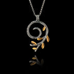 a silver spiral olive branch pendant on a chain, featuring an oxidized stem and gold-plated leaves.