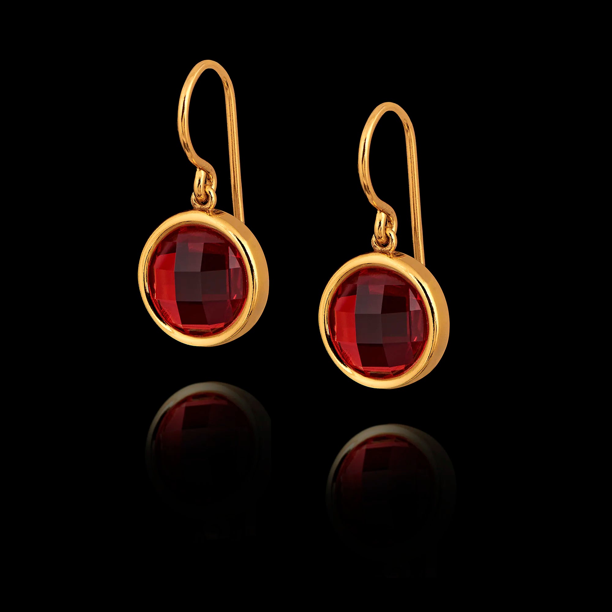 Gold earrings with red gemstones on a black background
