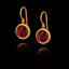 Gold earrings with red gemstones on a black background
