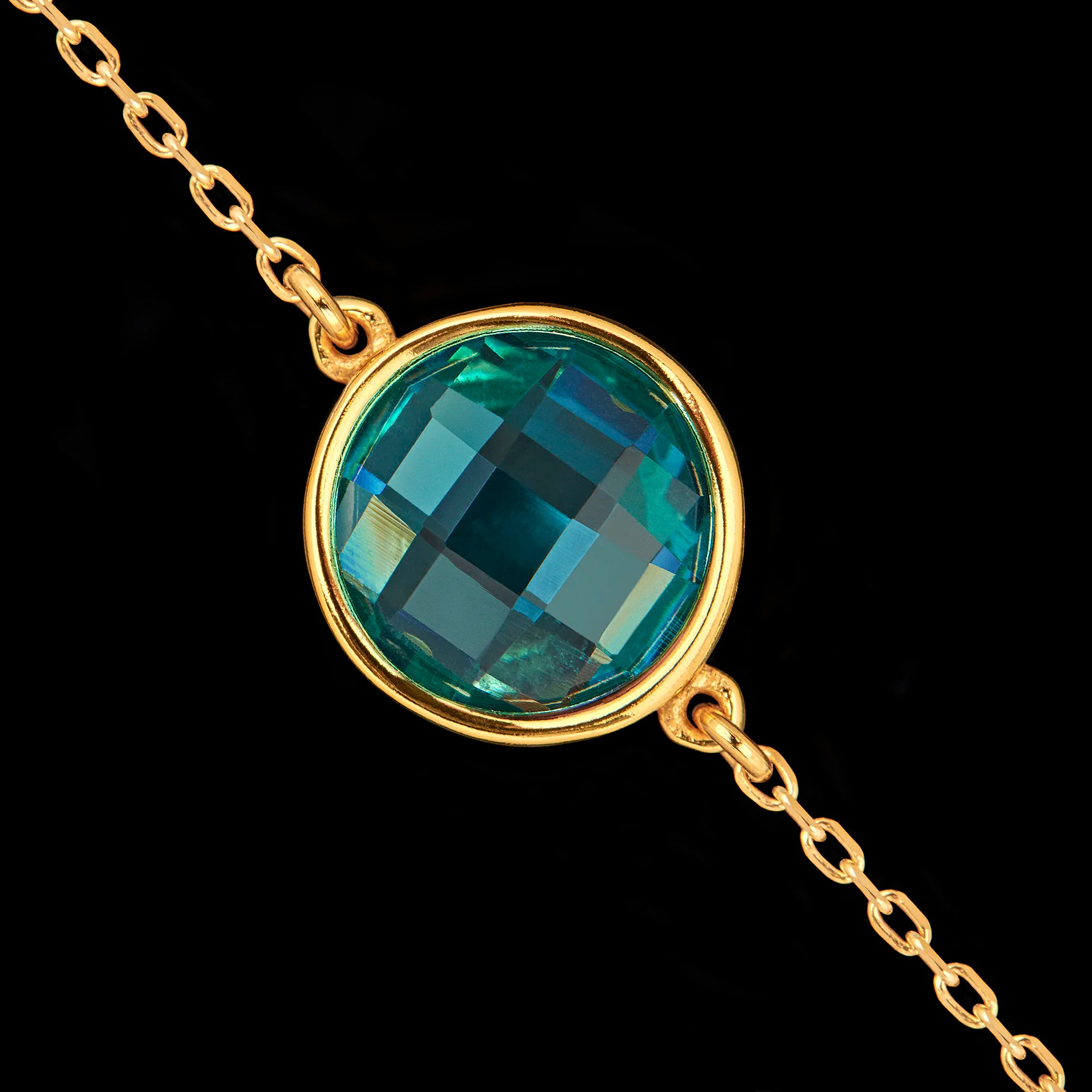 Close-up detail of the round faceted synthetic emerald gemstone set in a gold-plated bezel.