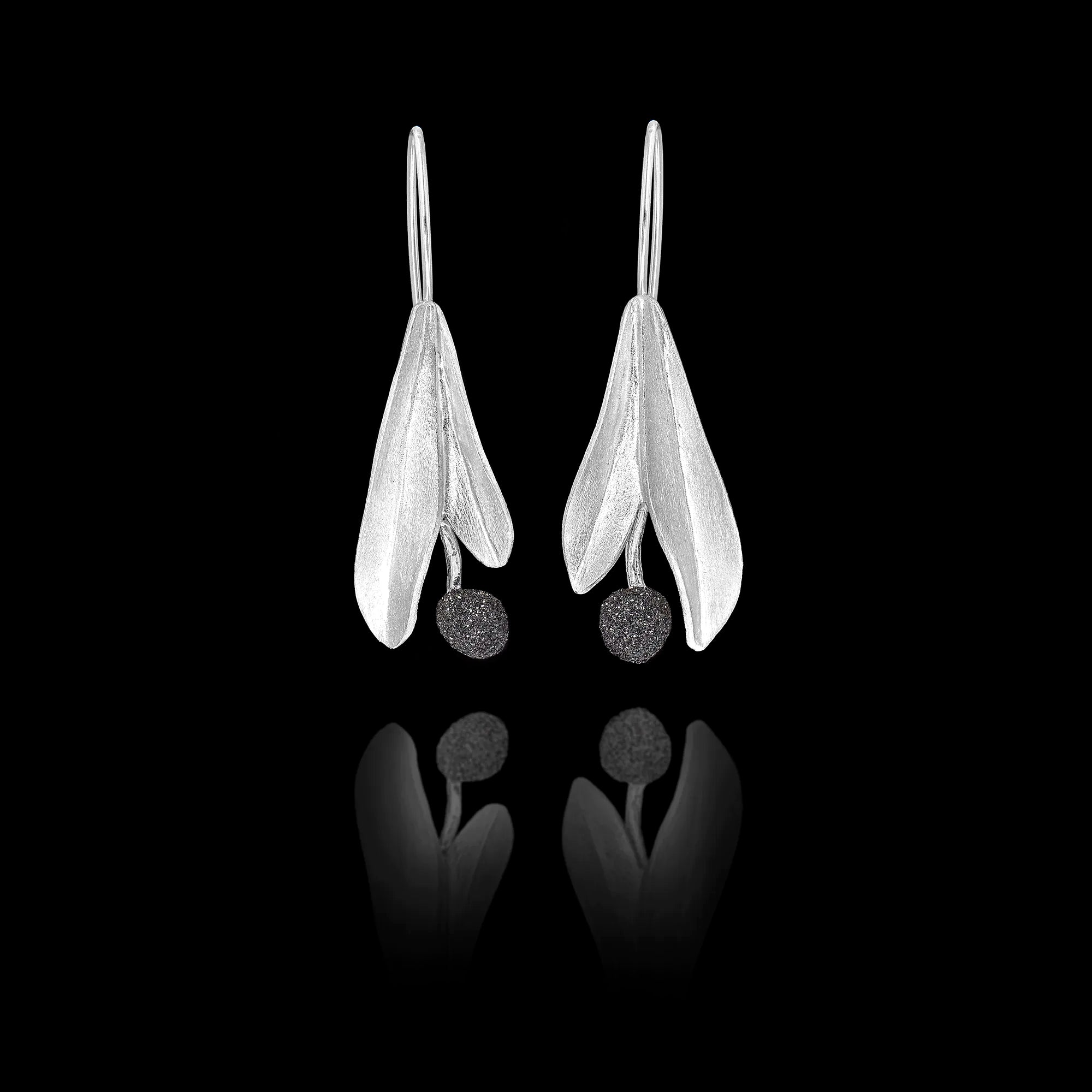 Front view of silver drop earrings featuring two matte-finish leaves with a dark, textured round gemstone at the bottom.