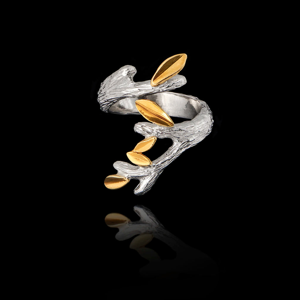 Top view of a silver and gold ring featuring a detailed branch design with textured olive leaves on a black background