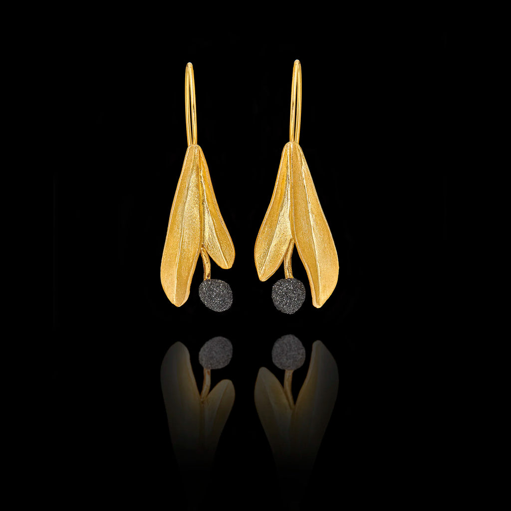Gold leaf-shaped earrings with black stones on a black background