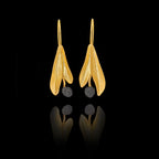 Gold leaf-shaped earrings with black stones on a black background