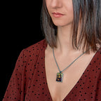 Woman wearing a necklace with a pendant resembling 'Mona Lisa' on a plain background
