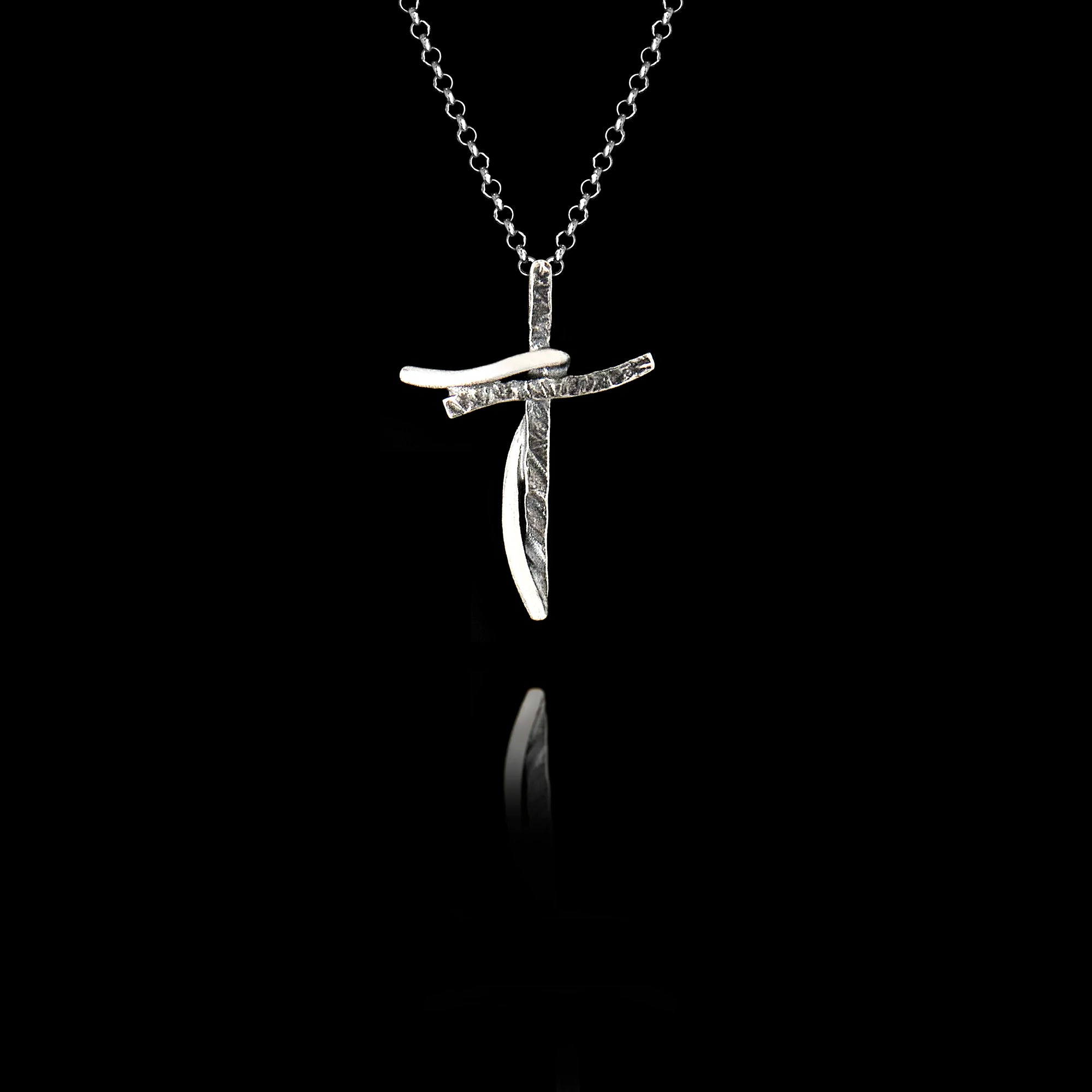 An oxidised silver cross pendant featuring on a black background. Main image
