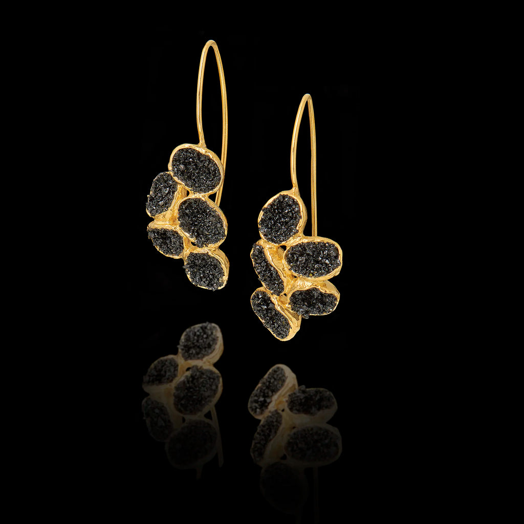 Gold earrings with black druzy stones on a black background