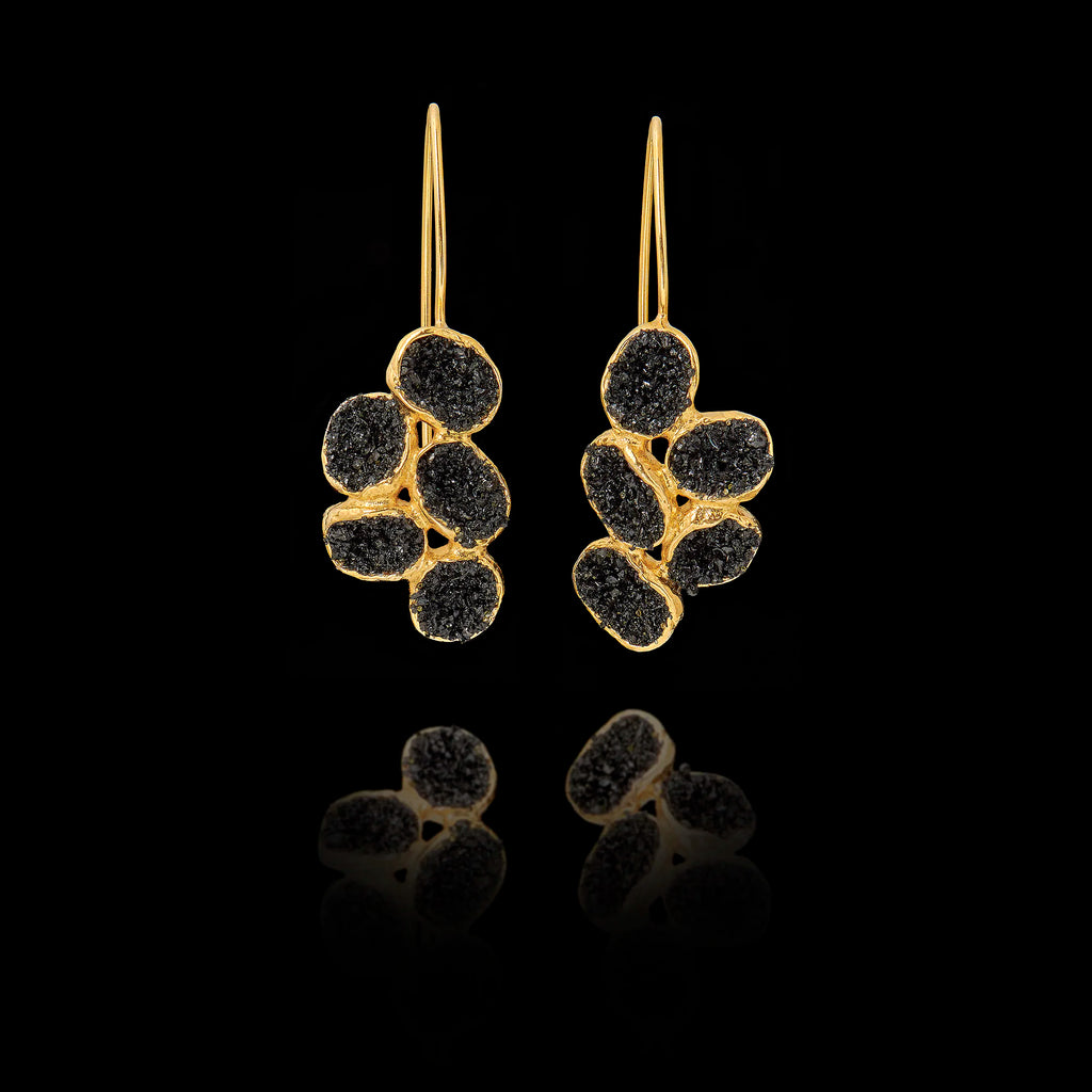 Gold earrings with black gemstones on a black background