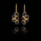 Gold earrings with black gemstones on a black background