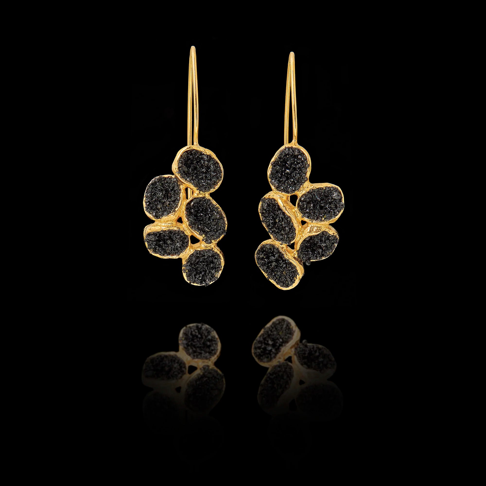 Gold earrings with black gemstones on a black background Main image
