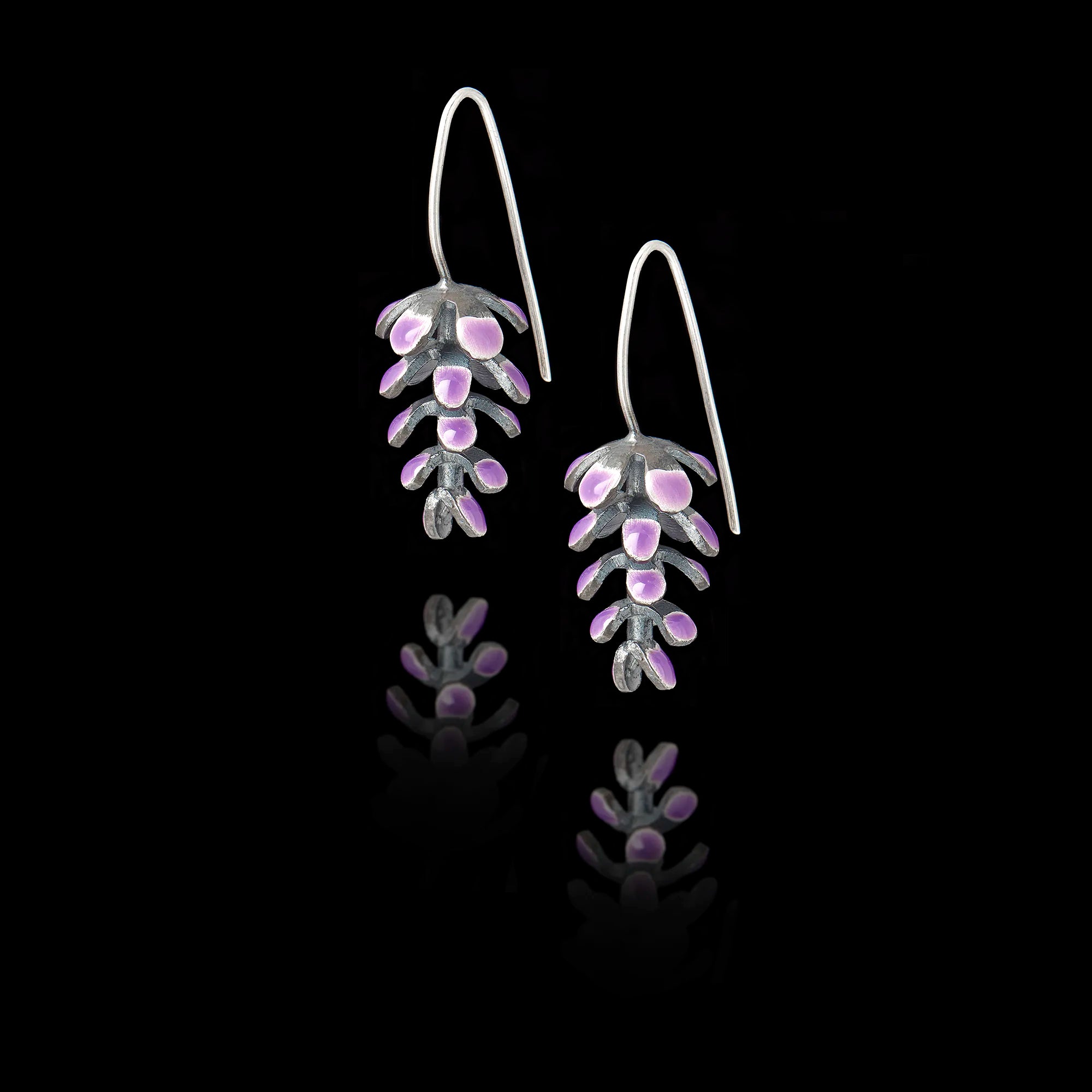 Perspective view of the lavender drop earrings showing the detailed enamel work and long silver hook fastenings.