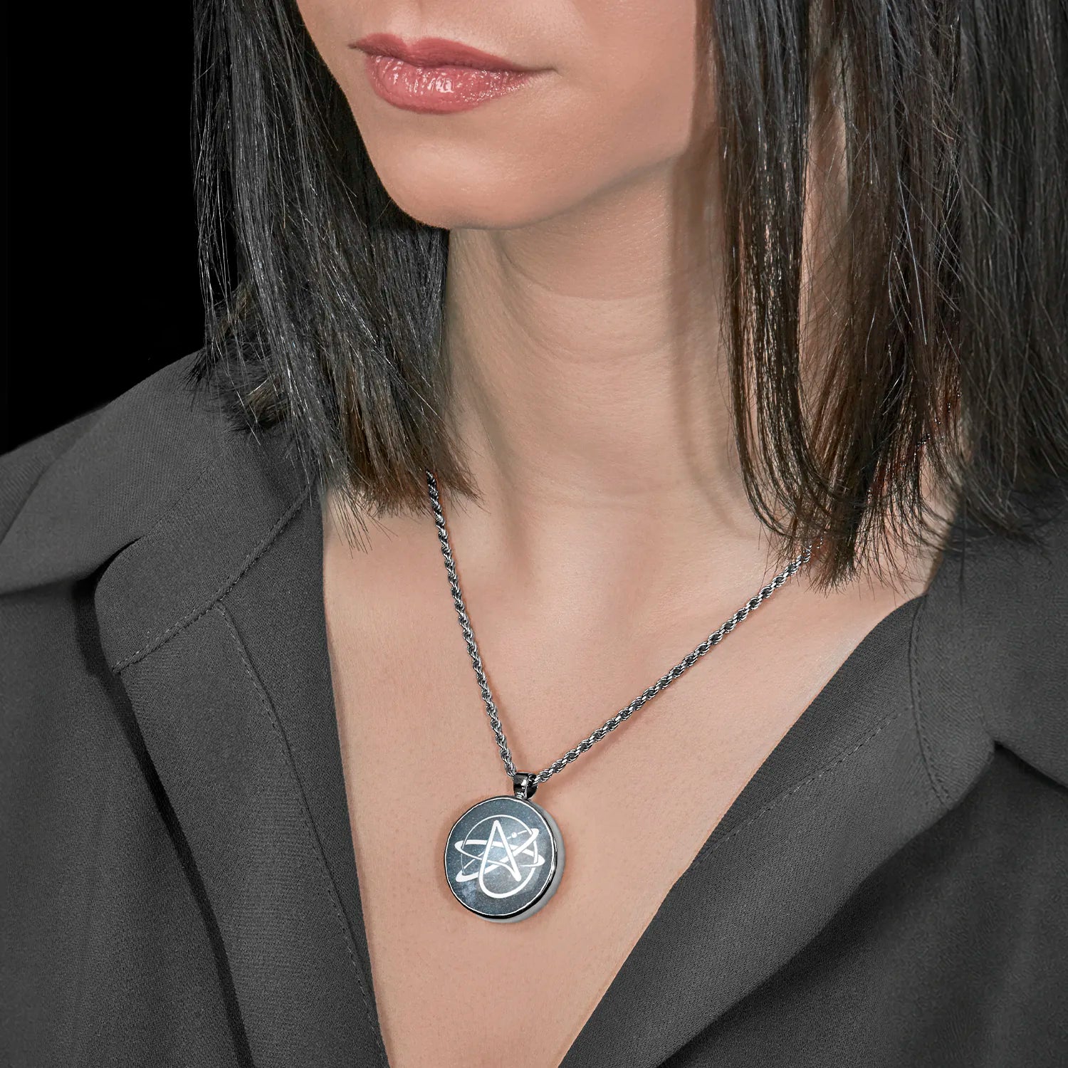 Person wearing a necklace with a Round 925 sterling silver pendant featuring the white Atheist Atomic symbol set against a deep blue starry galaxy background.