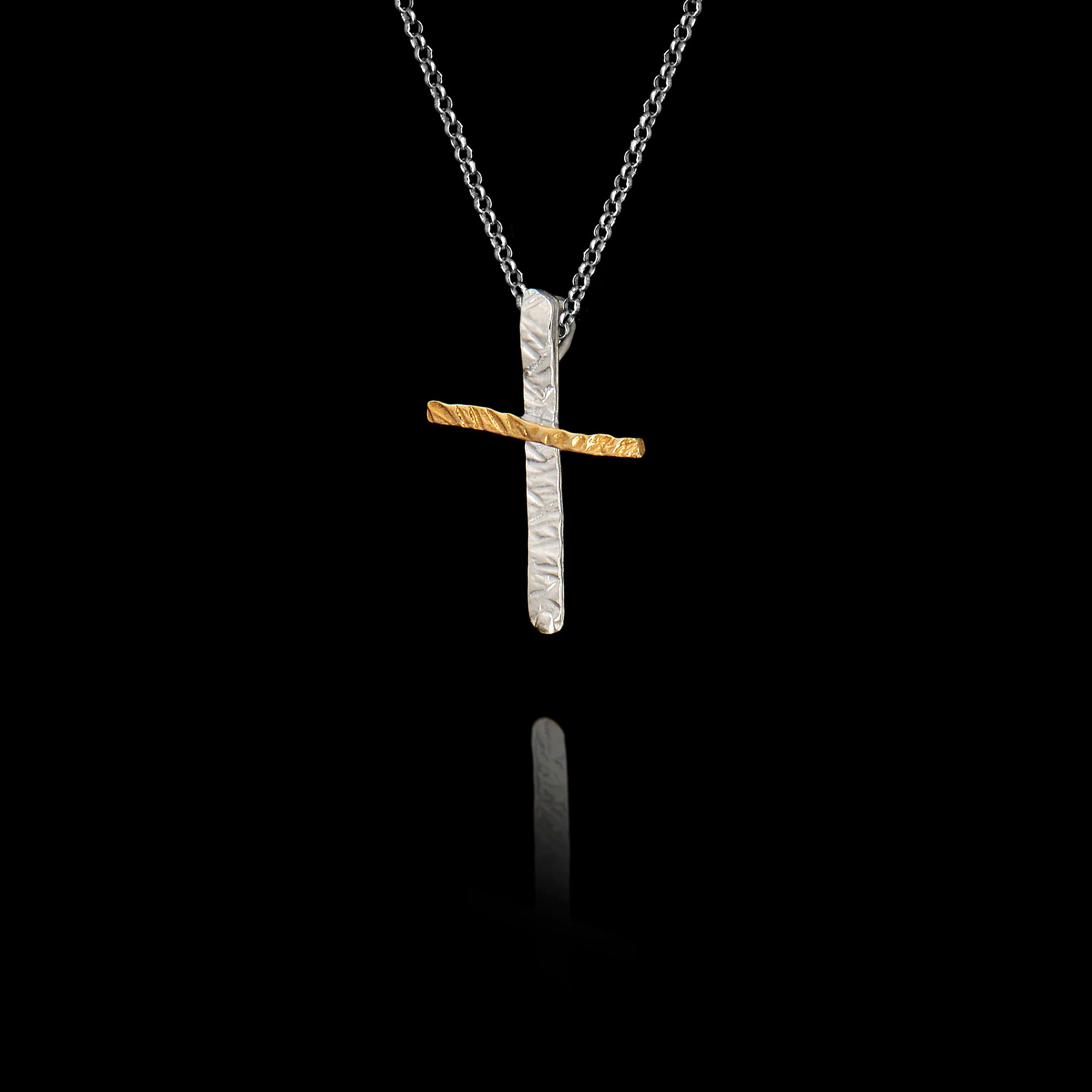 Side angle view of a handcrafted 925 sterling silver two-tone cross pendant showing the hammered rhodium-plated and gold-plated finish on a silver chain against a black background.