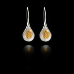 Front view of silver teardrop earrings with  gold cluster of fig seeds inside.