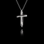 Handcrafted 925 sterling silver modern cross pendant featuring a sculptural double-bar design with oxidised and rhodium-plated finish, on a silver chain against a black background.