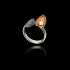 Perspective view of the oxidized shell ring highlighting the textured surface, the dark patina, and the pearl nestled in the golden shell interior