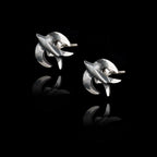 Angled side view of a pair of silver stud earrings shaped like swallows with a dark oxidized finish.