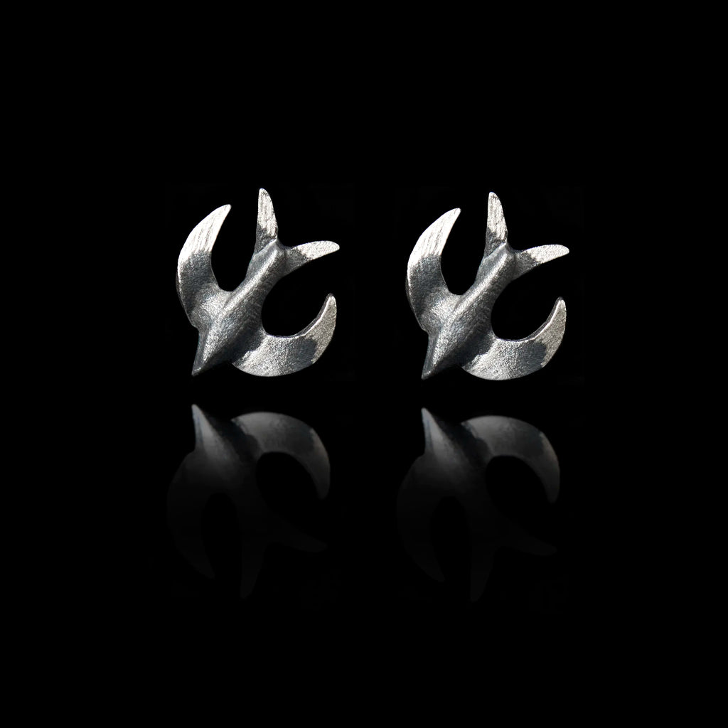 Front view of a pair of silver stud earrings shaped like swallows with a dark oxidized finish.