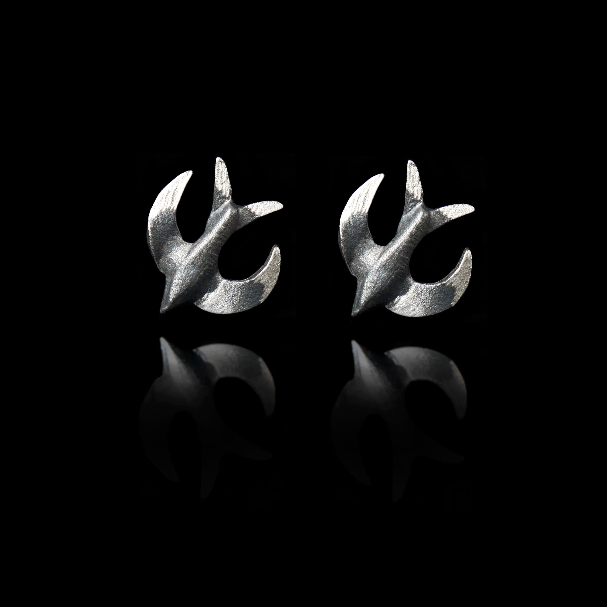 Front view of a pair of silver stud earrings shaped like swallows with a dark oxidized finish.