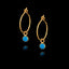 Gold hoop earrings with turquoise gemstones on a black background