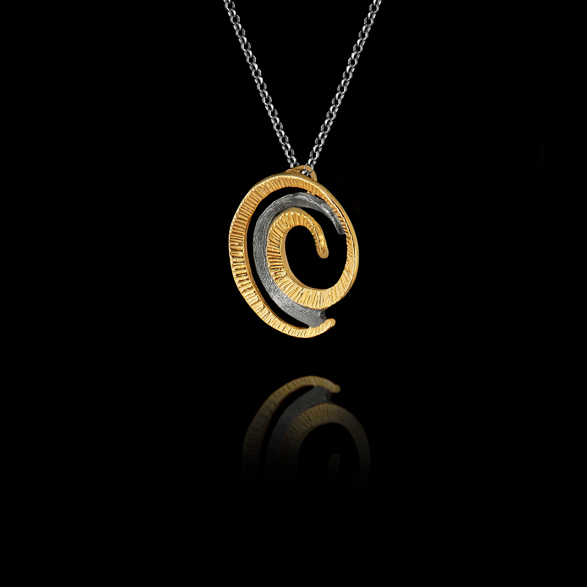 Side angle view of a handcrafted 925 sterling silver spiral pendant showing the layered gold-plated and oxidised silver coils with fine ridged texture on a silver chain against a black background.
