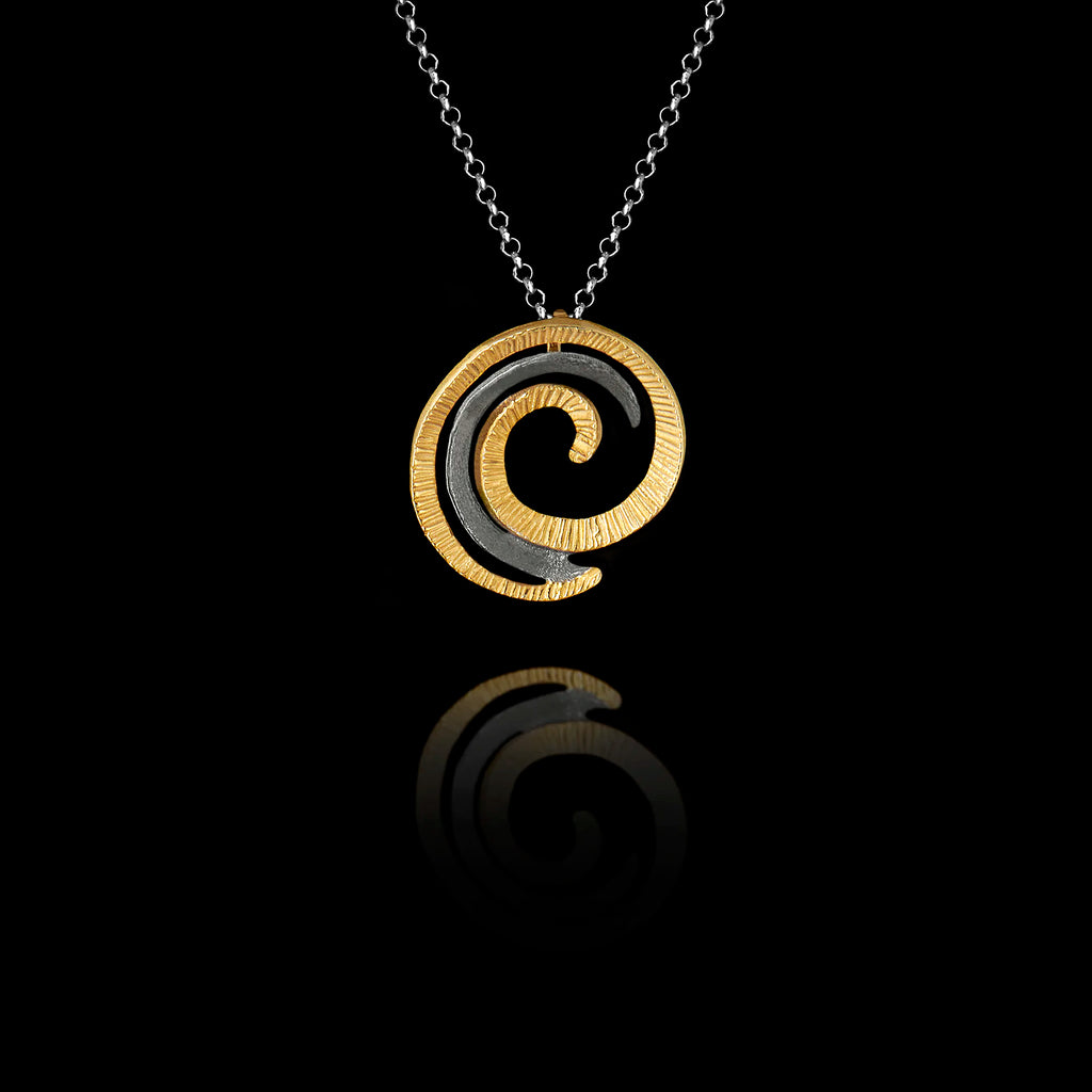 Handcrafted 925 sterling silver spiral pendant featuring a ridged gold-plated outer coil and oxidised silver inner curl, hanging on a silver chain against a black background.