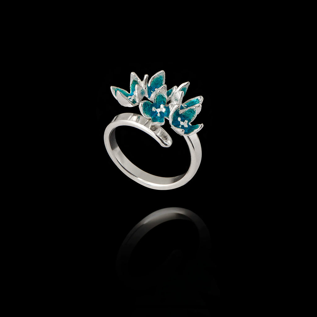 Angled view of an adjustable 925 sterling silver ring featuring a cluster of five flowers with bright turquoise enamel petals.