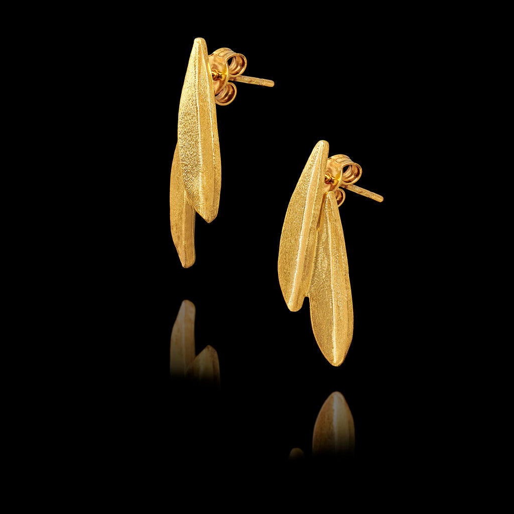 Angled side view of a pair of gold stud earrings shaped like olive leaves on a black background