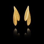 A pair of gold stud earrings shaped like olive leaves on a black background