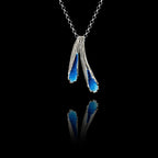 Handcrafted 925 sterling silver marine-inspired pendant featuring two textured silver forms filled with vivid blue crushed enamel crystals, hanging on a silver chain against a black background.
