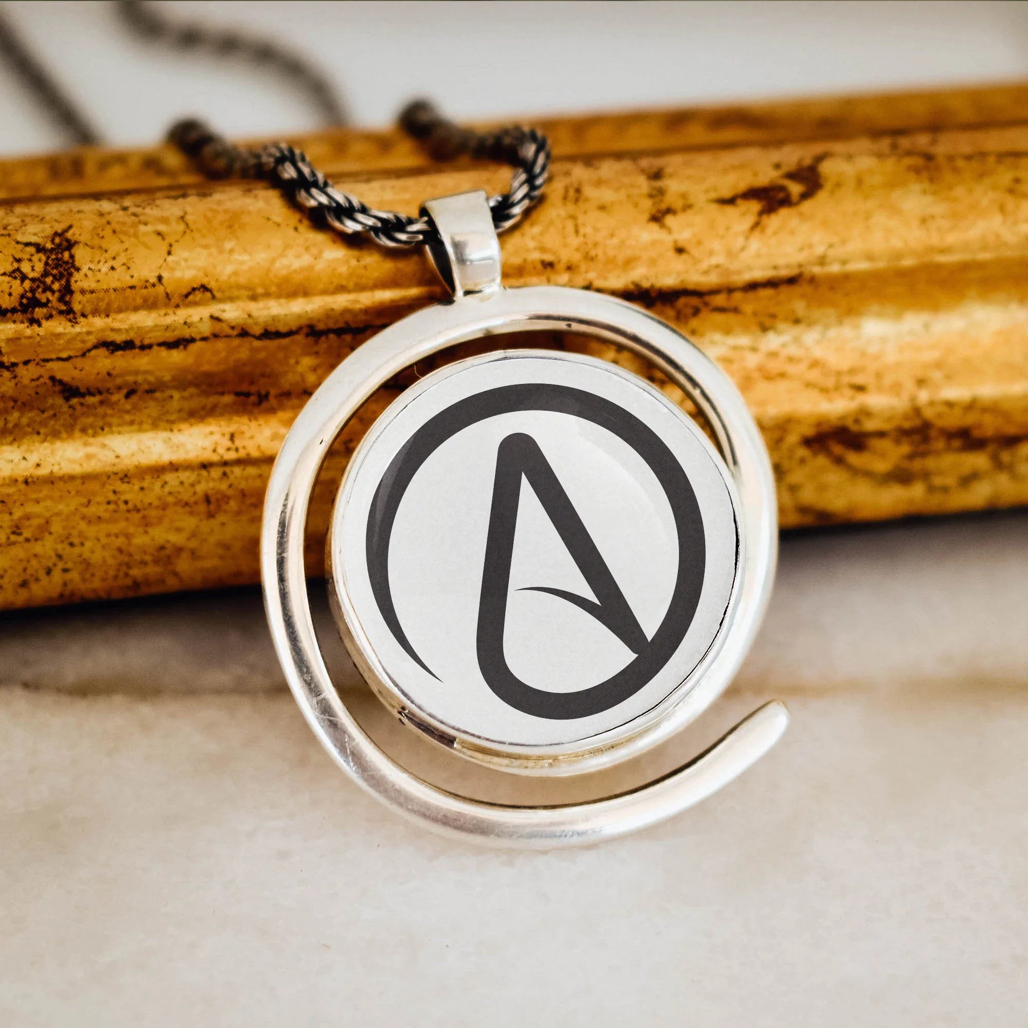 Silver pendant with an atheist symbol on a wooden surface