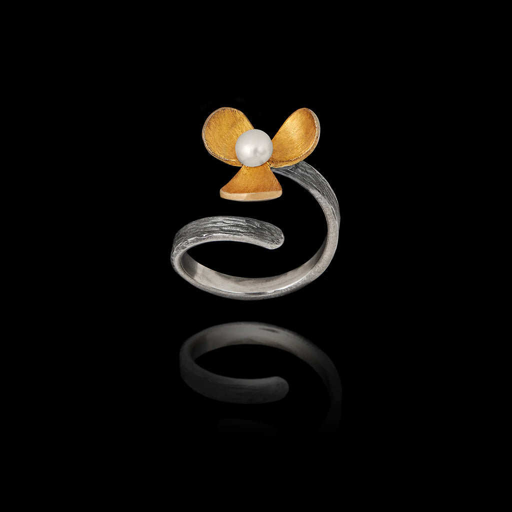 Perspective view of an adjustable silver ring featuring an oxidized flower with a gold-plated center and a pearl.