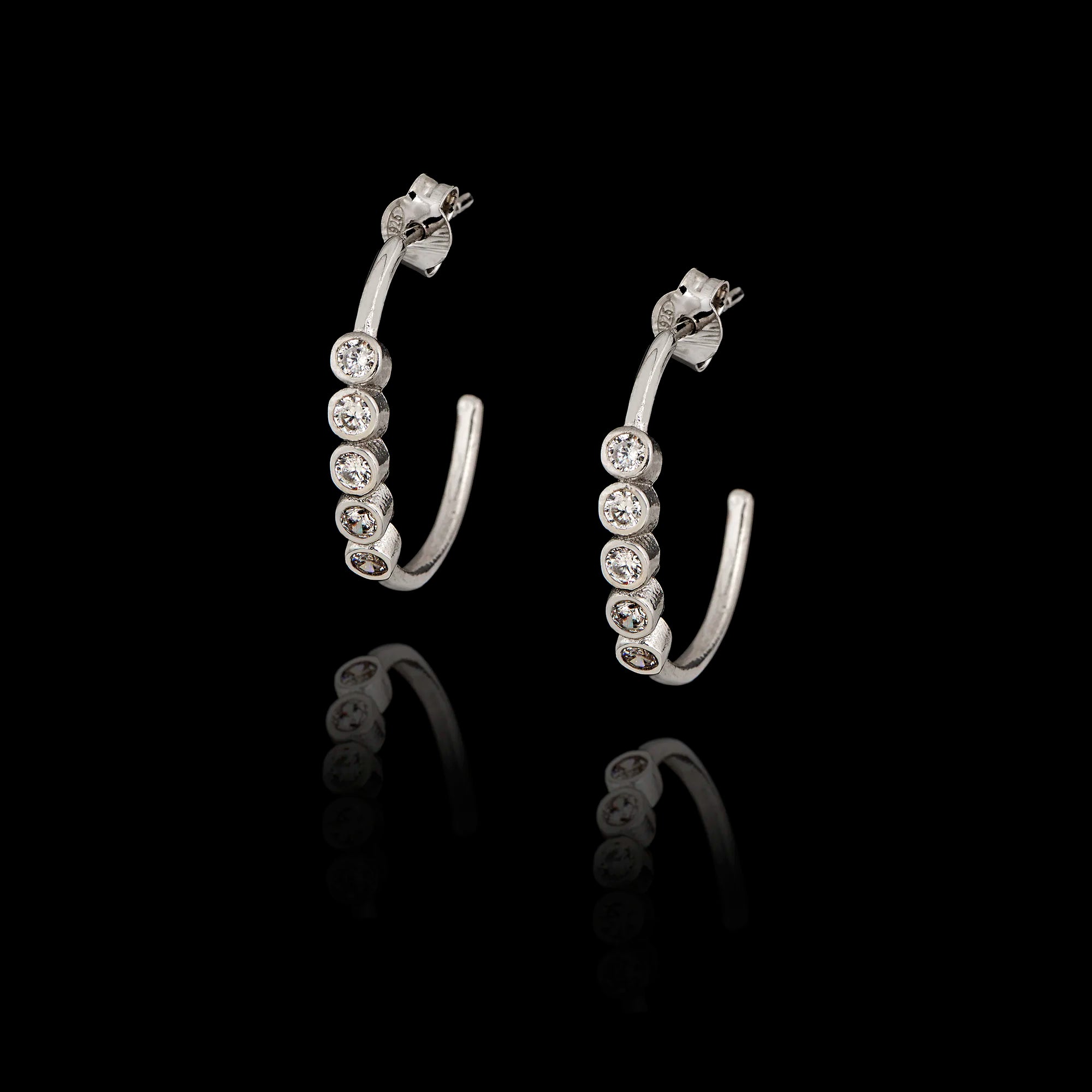 Sterling silver hoop earrings featuring a front-facing row of five round sparkling zircon stones in a black background.
