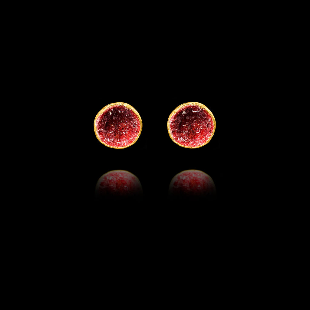Front view of gold stud earrings featuring circular crimson garnet druzy stones