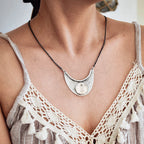 Necklace with a large, intricate pendant worn by a person in a lace top.
